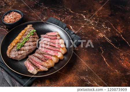 Sliced grilled medium rare Top sirloin beef steak on a plate. Dark background. Top view. Copy space Sliced grilled medium rare Top sirloin beef steak on a plate. Dark background. Top view. Copy space 120873909