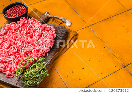 Fresh Raw Mince, Ground beef and pork meat on a butcher board. Orange background. Top view. Copy space 120873912