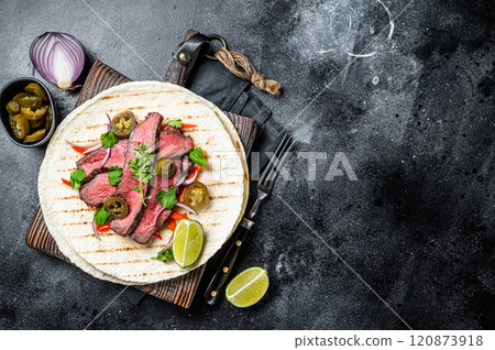 Tacos of mexican beef fajitas alambre with onion, jalapeno and bell pepper. Black background. top view. copy space 120873918