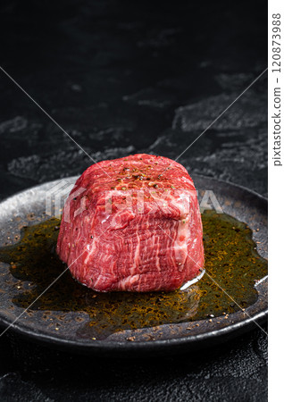 Fillet Mignon prime beef steak, raw dry aged marble meat with herbs and spices ready for cooking. Black background. Top view 120873988