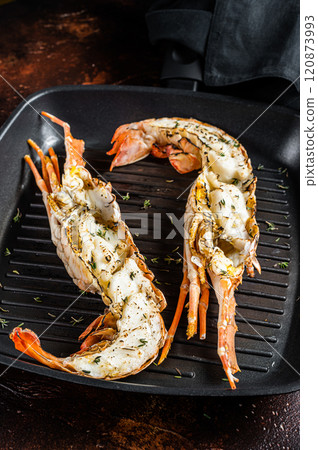 Delicious grilled and sliced Spiny lobster or sea crayfish. Dark background. Top view Delicious grilled and sliced Spiny lobster or sea crayfish. Dark background. Top view 120873993
