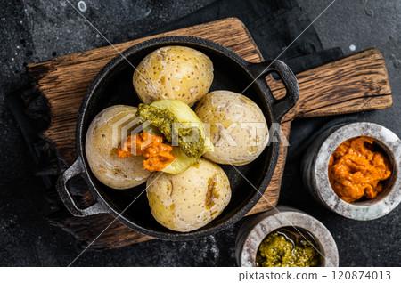 Papas arrugadas Canary islands wrinkled potatoes with green and red sauces served in a skillet. Black background. Top view 120874013