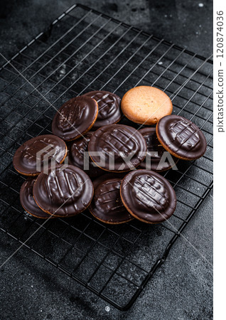 Jaffa Cakes, Cookies covered with dark chocolate and filled with orange marmalade. Black background. Top view 120874036