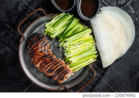 Peking Duck served with cucumber, green onions, and roasted wheaten chinese pancakes with sauce Hoysin. Black background. Top view 120874042