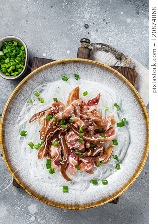 Salad with pork pig ears, glass noodles, sesame seeds and green onions. Fried pork ears in korean style. Gray background. Top view Salad with pork pig ears, glass noodles, sesame seeds and green onions. Fried pork ears in korean style. Gray background. Top view 120874068
