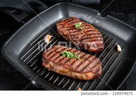 Grilled Top Blade or flat iron roast beef meat steaks on a skillet. Black background. Top View Grilled Top Blade or flat iron roast beef meat steaks on a skillet. Black background. Top View 120874075