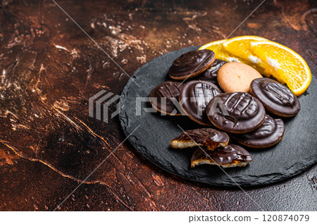 Stack of Chocolate Covered Round Jaffa Cookies with Orange Flavored Marmalade. Dark background. Top view. Copy space 120874079