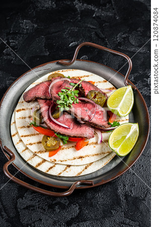 Carne Asada Tacos with grilled steak, green sauce, jalapenos and onion, Mexican food. Black background. top view 120874084