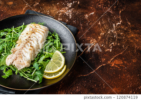 Grilled cod fish fillet served with green salad in a plate. Dark background. Top view. Copy space 120874119