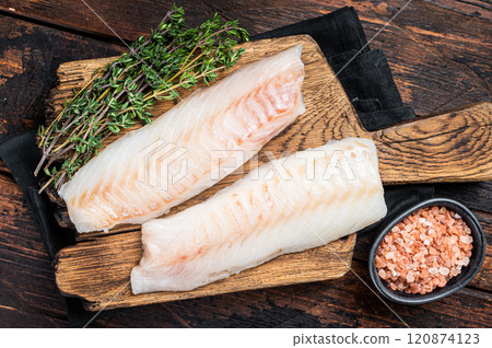 Cod fish fillets, raw codfish with thyme on wooden board. Wooden background. Top view 120874123