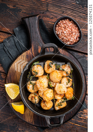 Scallops seared in garlic, thyme and butter served in cast iron skillet. Wooden background. Top view 120874131