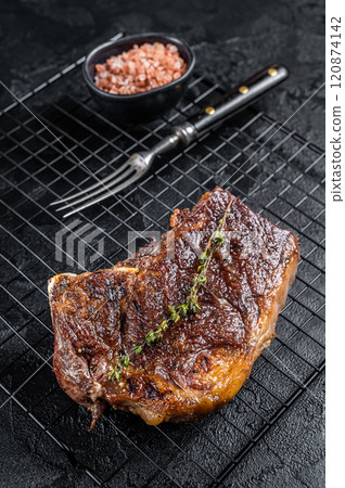 Grilled Striploin beef meat steak or new york steak on a grill rack. Black background. Top view 120874142