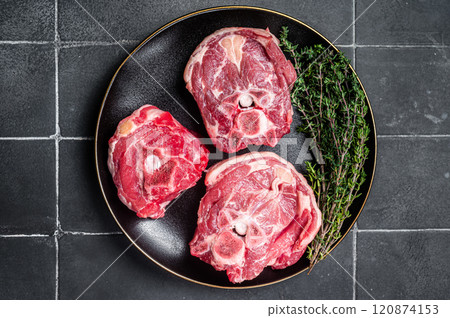 Raw Lamb Gerdan, lamb neck chops on a plate with herbs. Black background. Top view 120874153