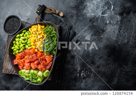 Hawaiian raw fish salad Poke bowl with Salmon, Cucumber, Edamame, and Rice. Black background. Top view. Copy space Hawaiian raw fish salad Poke bowl with Salmon, Cucumber, Edamame, and Rice. Black background. Top view. Copy space 120874154