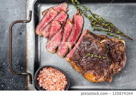 Grilled Wagyu Striploin beef meat steak or new york steak in a steel tray. Black background. Top view 120874164