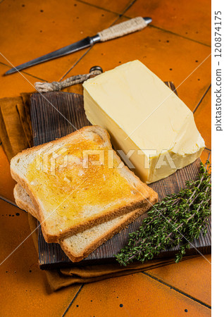 Spreading butter on toast with knife . Orange background. Top view Spreading butter on toast with knife . Orange background. Top view 120874175