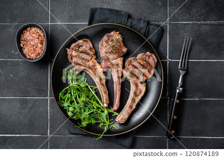 Roasted lamb meat cutlets, mutton chops with garnish. Black background. Top view Roasted lamb meat cutlets, mutton chops with garnish. Black background. Top view 120874189