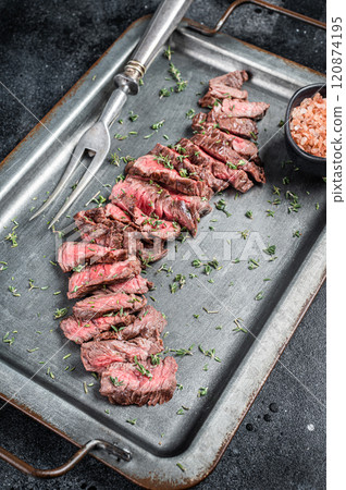 BBQ Roast sliced Skirt beef meat steak in steel tray with thyme. Black background. Top view BBQ Roast sliced Skirt beef meat steak in steel tray with thyme. Black background. Top view 120874195