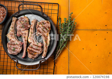 BBQ with Grilled lamb meat chops, mutton steaks with herbs. Orange background. Top view. Copy space 120874198