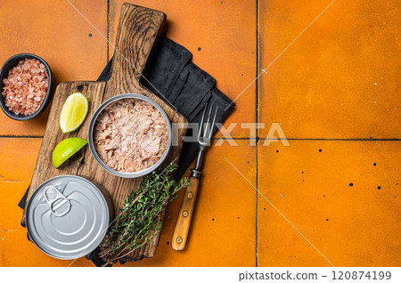 Tin with Canned tuna fillet meat in olive. Orange background. Top view. Copy space 120874199