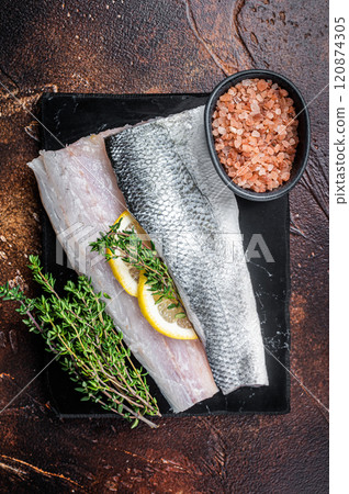 Sea Bass fillets, Raw Seabass fish with thyme, pink salt and lemon on marble board. Dark background. Top view 120874305
