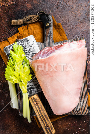 Fresh Raw pork shank knuckle on a butcher board with herbs for cooking. Dark background. Top view 120874308