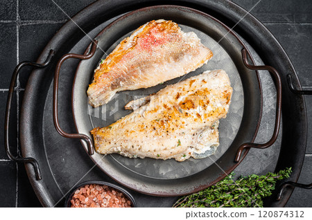 Roasted ocean red perch fillet with olive oil, thyme and spices. Black background. Top view 120874312