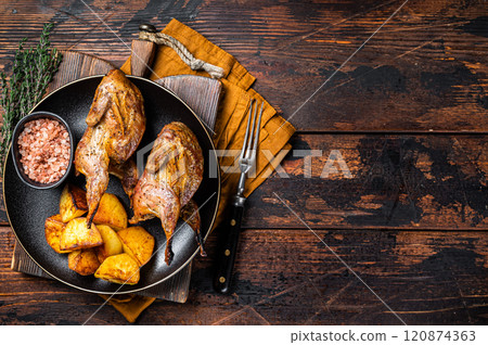 Roast whole quails in a plate with fried potato. Wooden background. Top view. Copy space 120874363