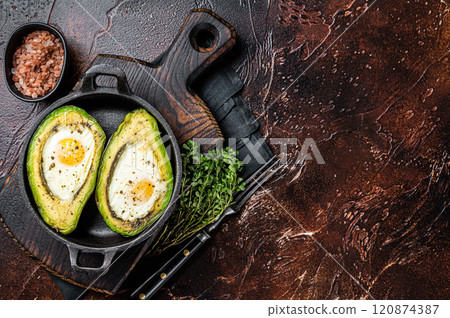 Baked Avocado with Egg, Salt, thyme and Pepper. Dark background. Top view. Copy space Baked Avocado with Egg, Salt, thyme and Pepper. Dark background. Top view. Copy space 120874387