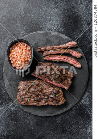 Traditional barbecue skirt steak sliced on a cutting board. Black background. Top view Traditional barbecue skirt steak sliced on a cutting board. Black background. Top view 120874394
