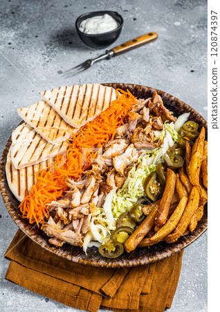 Chicken Shawarma Doner kebab on a plate with french fries, vegetables and salad. Gray background. Top view Chicken Shawarma Doner kebab on a plate with french fries, vegetables and salad. Gray background. Top view 120874397