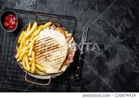 Doner kebab sandwich in grilled pita bread with vegetables and chicken meat. Black background. Top view. Copy space 120874414