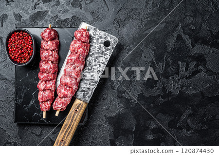 Raw beef Kofta kebab Skewers on a meat cleaver. Black background. Top view. Copy space Raw beef Kofta kebab Skewers on a meat cleaver. Black background. Top view. Copy space 120874430