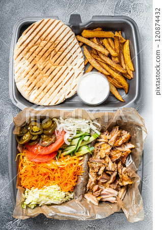 Doner kebab Shawarma on a plate with french fries and salad in box to go, take away. White background. Top view 120874432