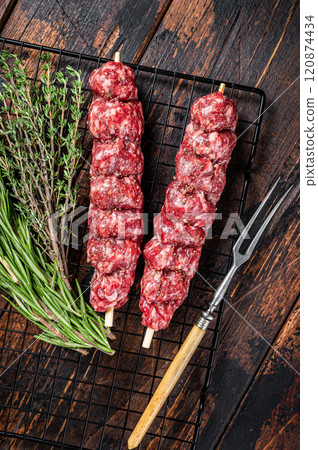Raw kofta, kofte kebab Skewers with beef and lamb meat and spices ready for cooking. Wooden background. Top view Raw kofta, kofte kebab Skewers with beef and lamb meat and spices ready for cooking. Wooden background. Top view 120874434