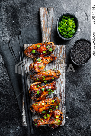 Chicken buffalo wings in sweet and sour sauce with black sesame. Black background. Top view Chicken buffalo wings in sweet and sour sauce with black sesame. Black background. Top view 120874443