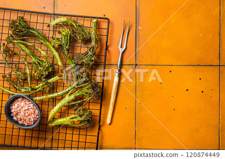Grilled Broccolini Sprouts with garlic. Orange background. Top view. Copy space 120874449