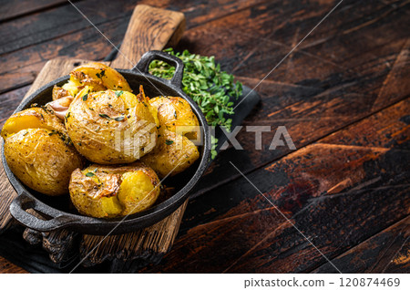 Crushed, Broken potatoes baked in oil with herbs. Wooden background. Top view. Copy space 120874469