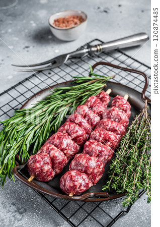 Raw Turkish Urfa kebab decorated with herbs, spices and meat fork. Gray background. Top view 120874485