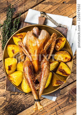 Roasted guinea fowl with herbs and potato, cooked farm eco bird. Wooden background. Top view 120874502