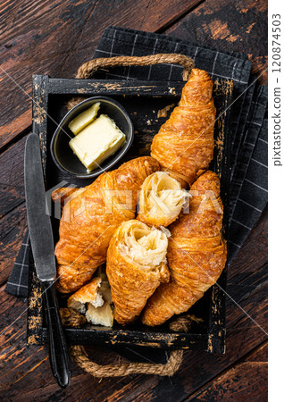 Pile of French buttered croissants with butter in wooden tray. Wooden background. Top view 120874503