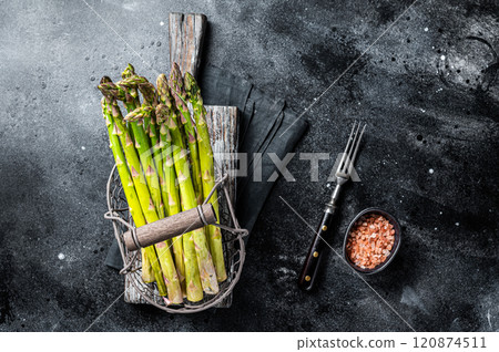 Fresh green asparagus in a basket. Black background. Top view Fresh green asparagus in a basket. Black background. Top view 120874511