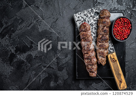 Urfa kebab, ground beef and lamb meat grilled on skewers. Black background. Top view. Copy space Urfa kebab, ground beef and lamb meat grilled on skewers. Black background. Top view. Copy space 120874529
