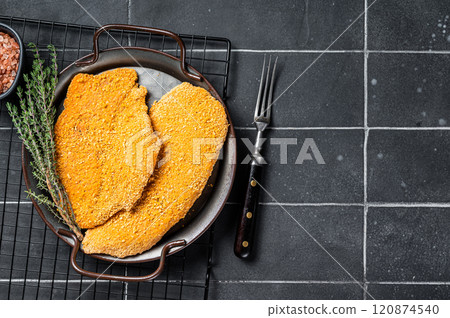 Homemade raw breaded German Weiner Schnitzel. Black background. Top view. Copy space Homemade raw breaded German Weiner Schnitzel. Black background. Top view. Copy space 120874540