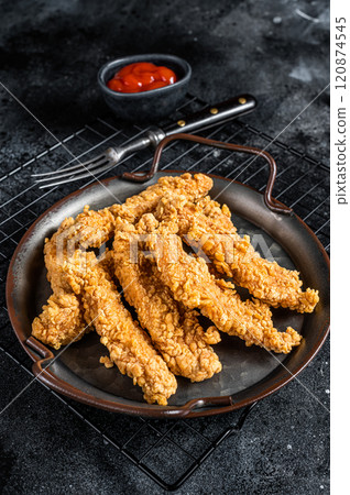Crispy chicken tenders strips with Ketchup. Black background. Top view Crispy chicken tenders strips with Ketchup. Black background. Top view 120874545