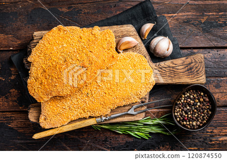 Uncooked Wiener schnitzel in breadcrumbs, raw pork meat. Wooden background. Top view Uncooked Wiener schnitzel in breadcrumbs, raw pork meat. Wooden background. Top view 120874550
