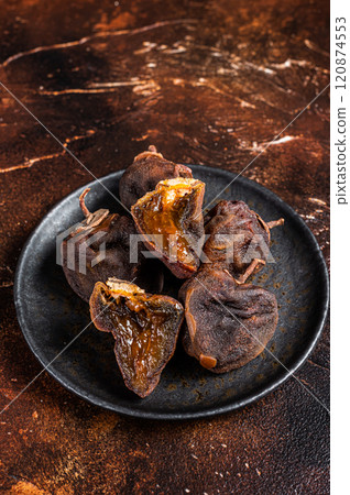 Dried persimmon fruit on a plate. Dark background. Top view Dried persimmon fruit on a plate. Dark background. Top view 120874553