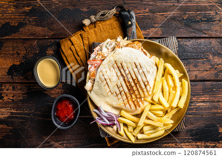Doner kebab, Shawarma in grilled pita bread with vegetables, meat and french fry. Wooden background. Top view Doner kebab, Shawarma in grilled pita bread with vegetables, meat and french fry. Wooden background. Top view 120874561