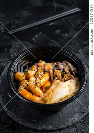Korean street food Tteokbokki, Topokki fried rice cake stick in spicy sauce. Black background. Top view Korean street food Tteokbokki, Topokki fried rice cake stick in spicy sauce. Black background. Top view 120874586