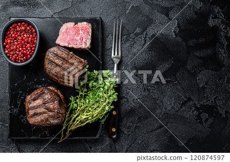 Grilled Fillet Mignon Steaks, dry aged beef tenderloin meat. Black background. Top view. Copy space Grilled Fillet Mignon Steaks, dry aged beef tenderloin meat. Black background. Top view. Copy space 120874597
